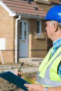 Licensed surveyor reviewing property documents and notes outside a residential home during a boundary survey update.

