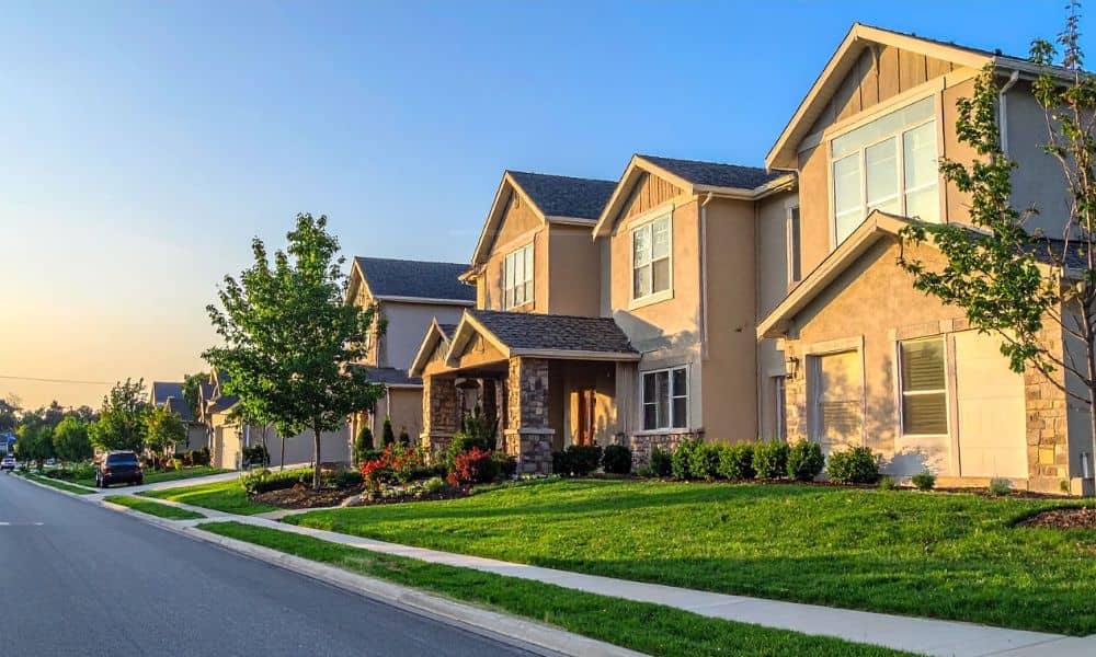  A suburban street with modern houses and well-maintained lawns, illustrating residential properties impacted by land use reforms and ALTA Land Title Survey requirements.
