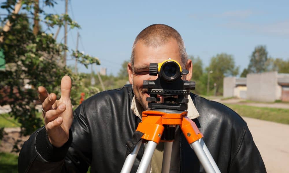 Land surveyor measuring property elevation certificate near residential area for flood insurance and home closing