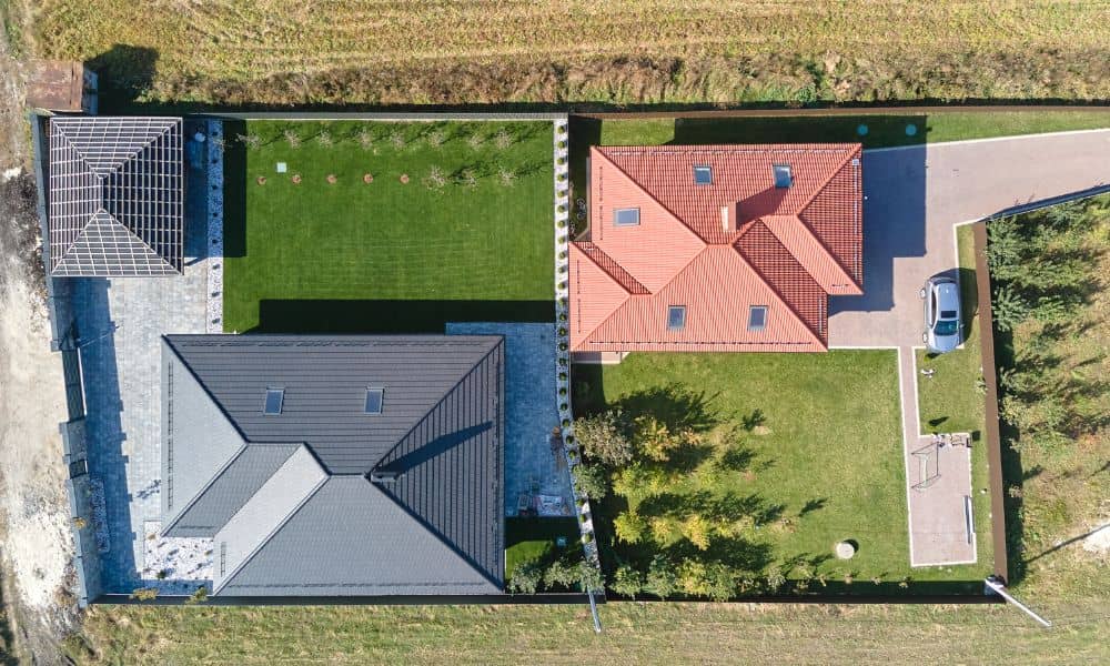 Drone surveying aerial view of two neighboring homes separated by a clear fence property line