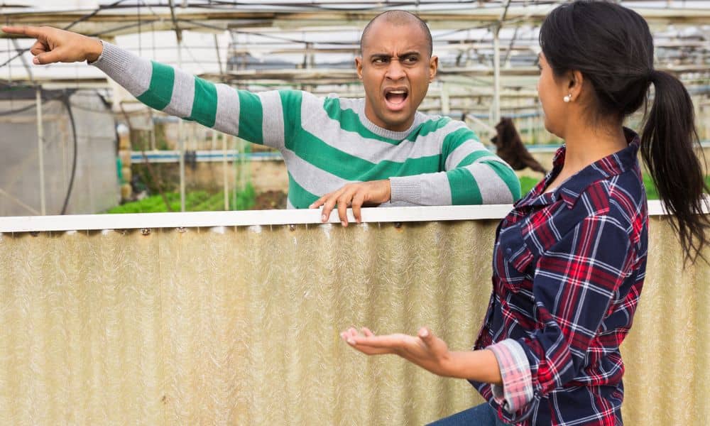 Two neighbors arguing over a shared fence before getting a property line survey