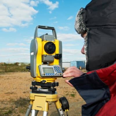 Land surveyor using a total station to complete a residential property survey
