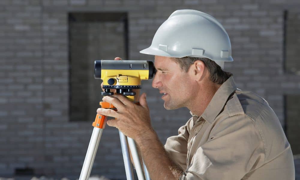 A construction surveyor using surveying equipment on an active job site