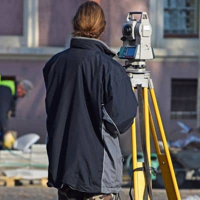 Licensed land surveyor taking field measurements for an elevation certificate using a total station