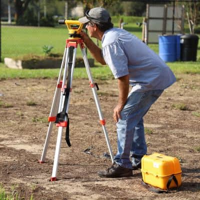 Cadastral surveyor using a total station to verify property boundary measurements