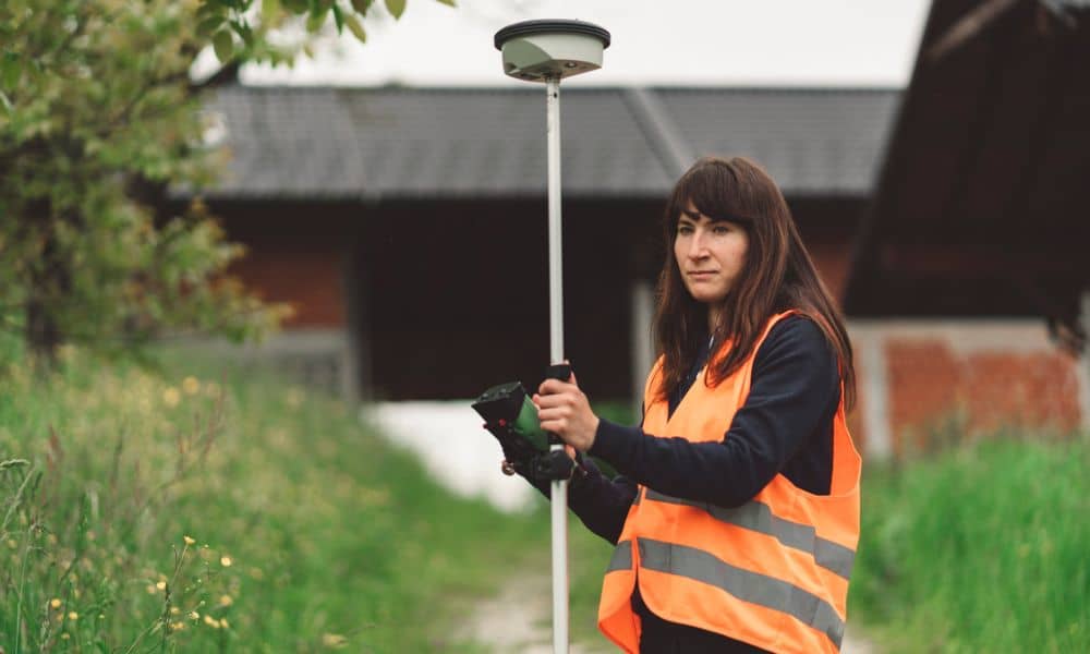 Professional from a land survey companies near me search using GPS equipment to check a property boundary