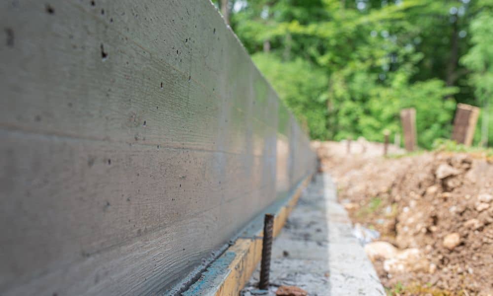 Metal rod in the ground beside a residential foundation, similar to property line markers used during housing development