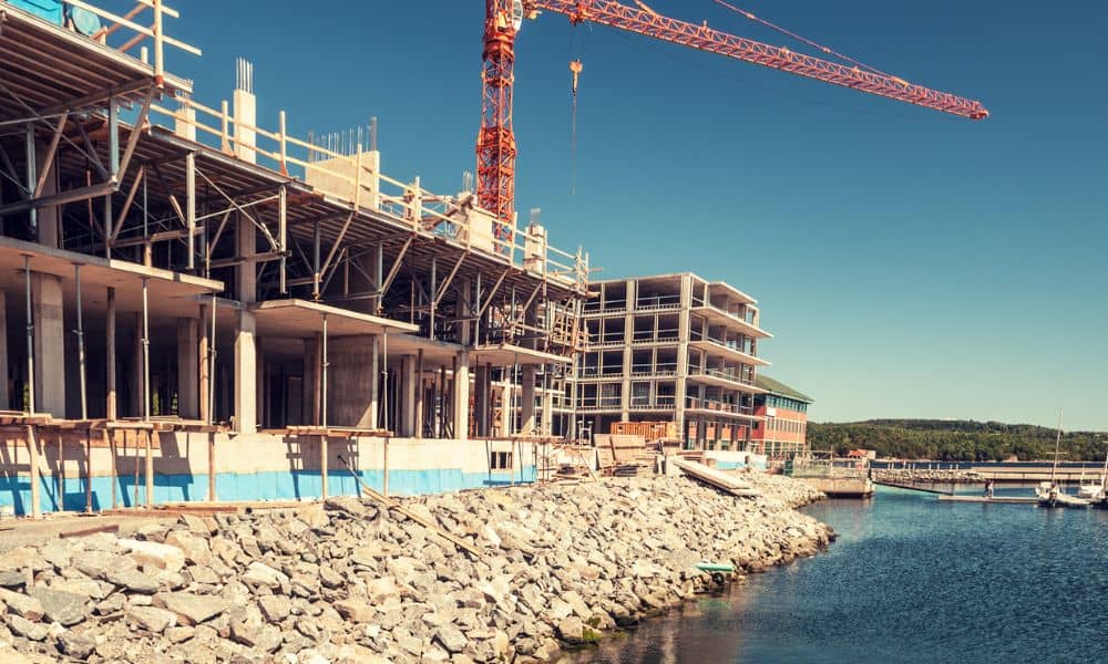 Licensed surveyor reviewing waterfront construction site near shoreline for permit approval